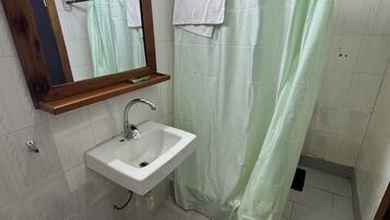 A bathroom with a sink, mirror, shower curtain, and a 'KEEP OFF' mat.
