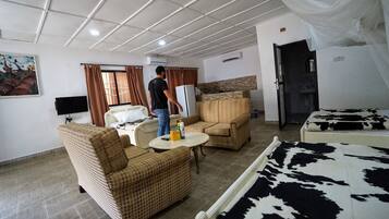 Camera d'albergo con un letto, due poltrone, un tavolino, una televisione e un quadro appeso al muro.