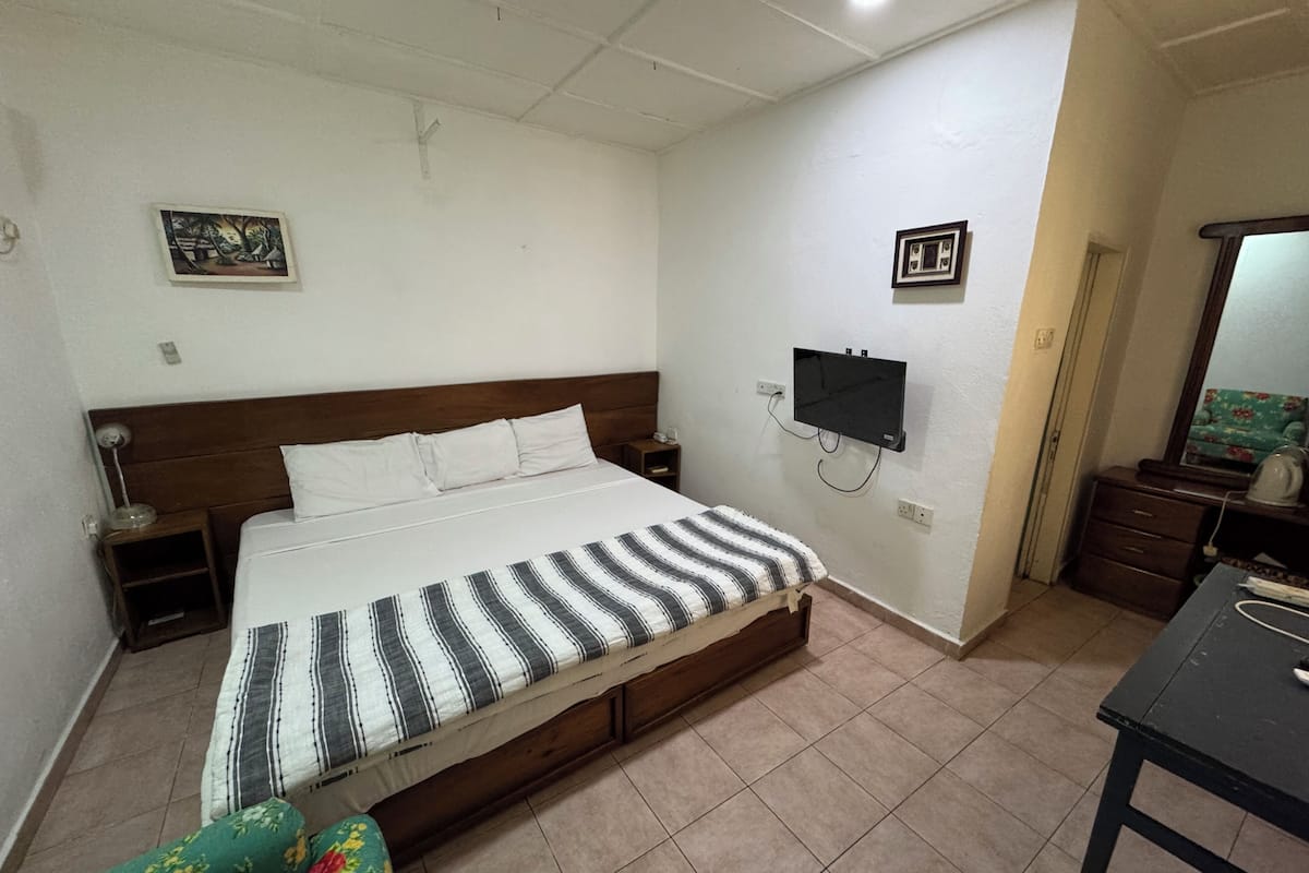 A bedroom with a bed, a TV, a dresser, and a chair.