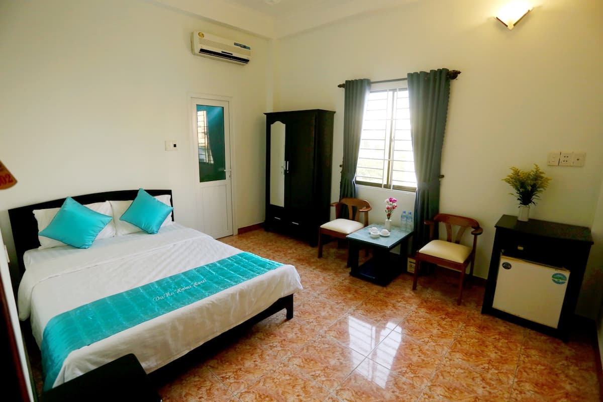 Une chambre d’hôtel équipée d’un lit, d’un bureau, d’une chaise, d’une armoire et d’un petit réfrigérateur.