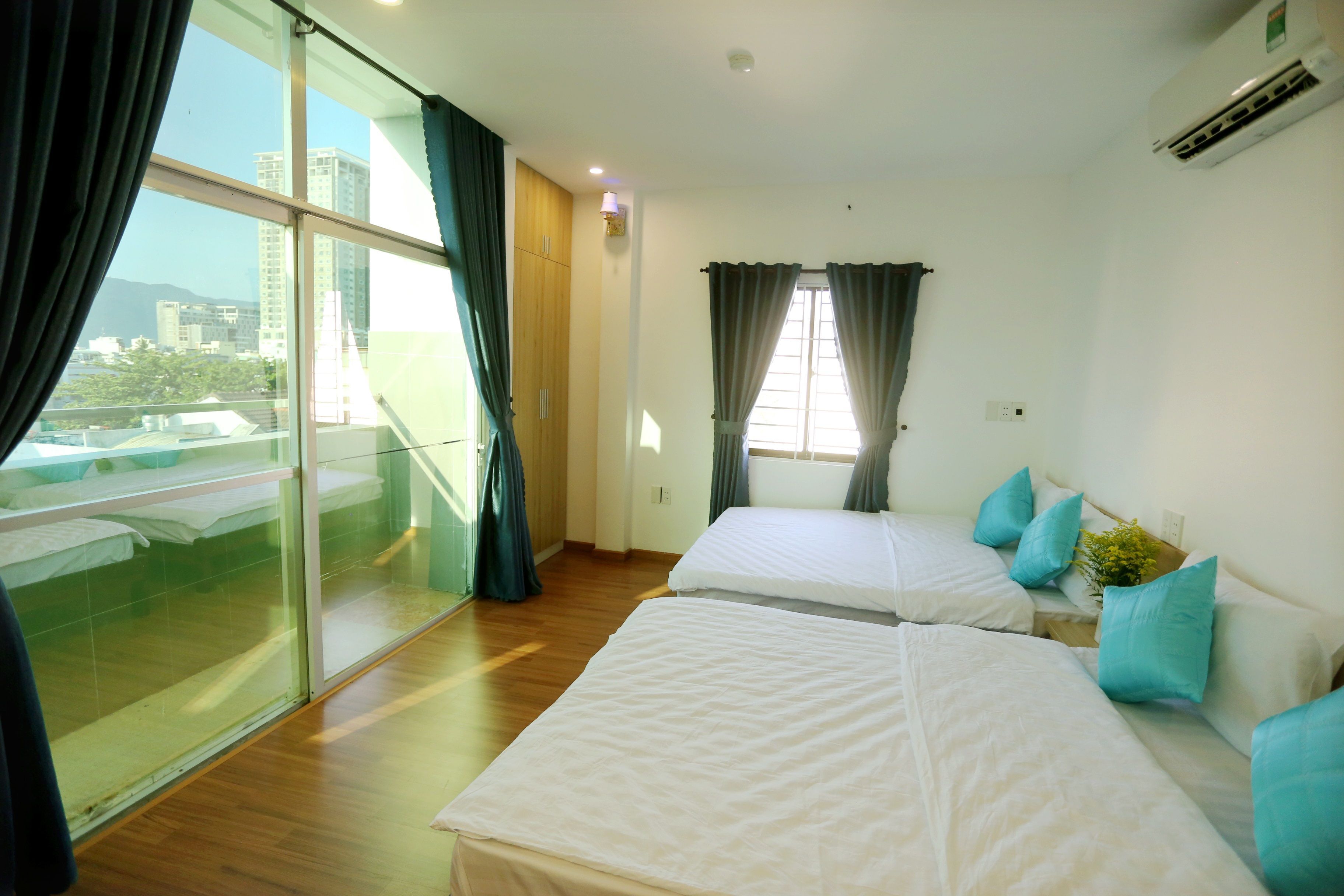 A hotel room with two beds, a large window, and a view of buildings.