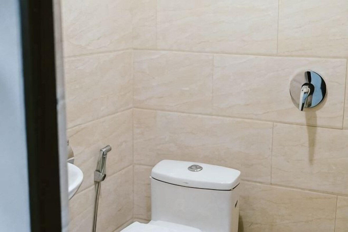 A small, enclosed bathroom with a toilet, a sink, and a shower.