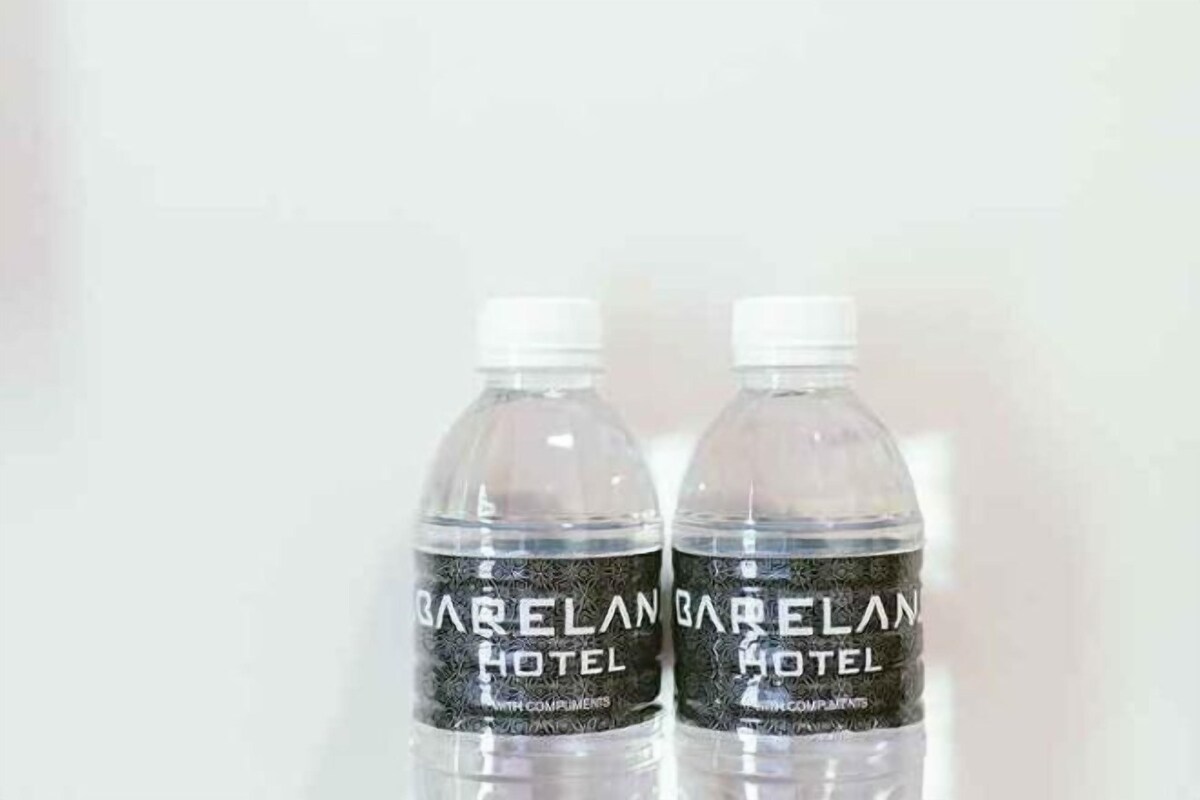 Two bottles of water labeled 'Garelan Hotel' with a white cap, placed on a reflective surface.