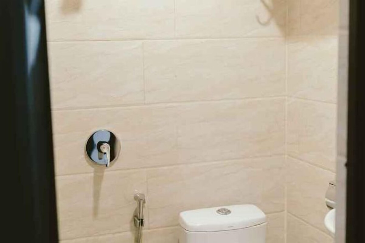 A bathroom with a toilet, a shower, and a wall-mounted faucet.