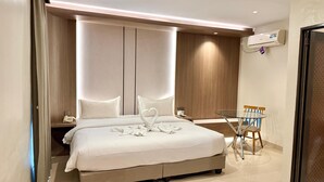 Una habitación de hotel moderna con una cama grande, una mesita de vidrio y una silla.