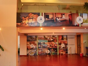 A hotel lobby with a large mural depicting various rooms and amenities. There are two circular signs with the hotel's logo. - Deluxe 4BR Penthouse By Unique Towers (Colombo)