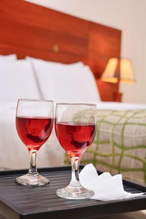 Two glasses of red beverage on a tray in front of a bed with white pillows and a wooden headboard. - Deluxe 4BR Penthouse By Unique Towers (Colombo)