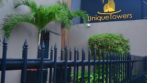 A building with a sign reading "UniqueTowers" and a black metal fence in front. - Deluxe 4BR Penthouse By Unique Towers (Colombo)