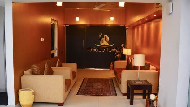 A hotel lobby with a reception desk, two sofas, a coffee table, a rug, and a decorative vase. - Deluxe 4BR Penthouse By Unique Towers (Colombo)