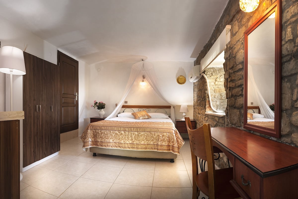 A bedroom with a bed, a nightstand, a mirror, and a wardrobe.