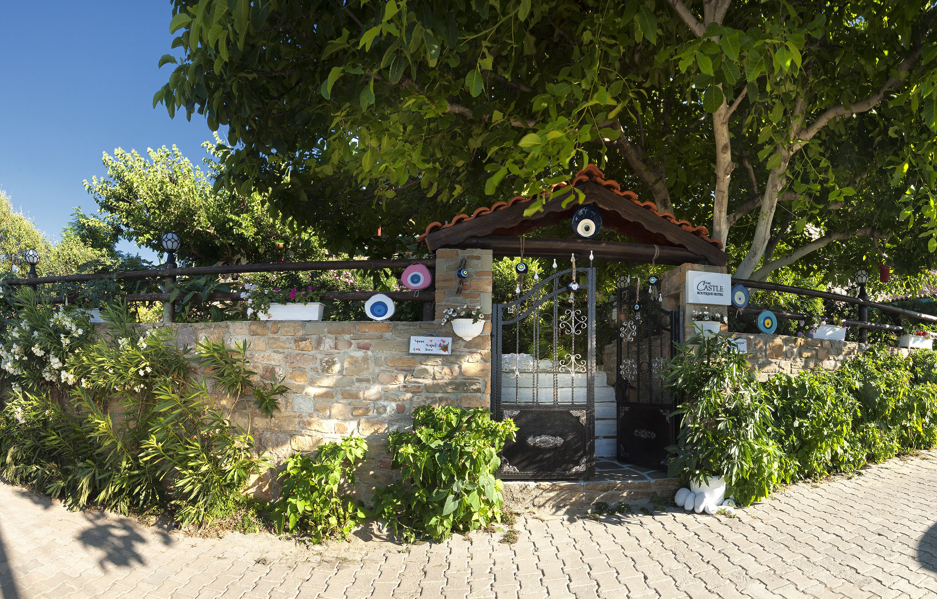 A stone wall with a gate, a sign reading "Castle Hotel," and a tiled roof structure.