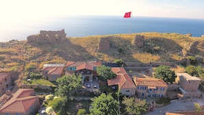 A coastal village with stone buildings, a flag, and a view of the sea. - The Castle (Gökçeada)