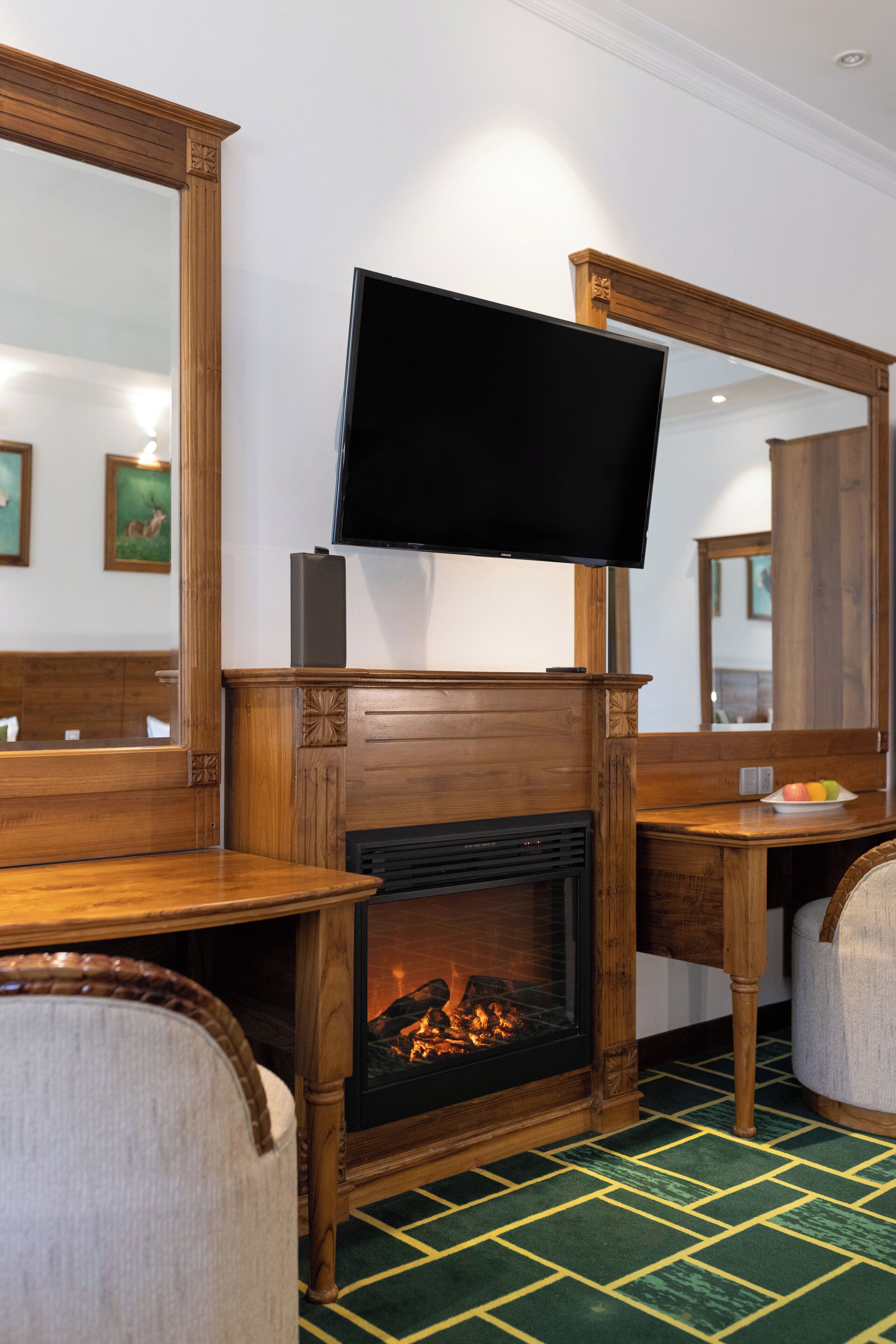 A room with a fireplace, a television mounted above it, and a large mirror on the wall.