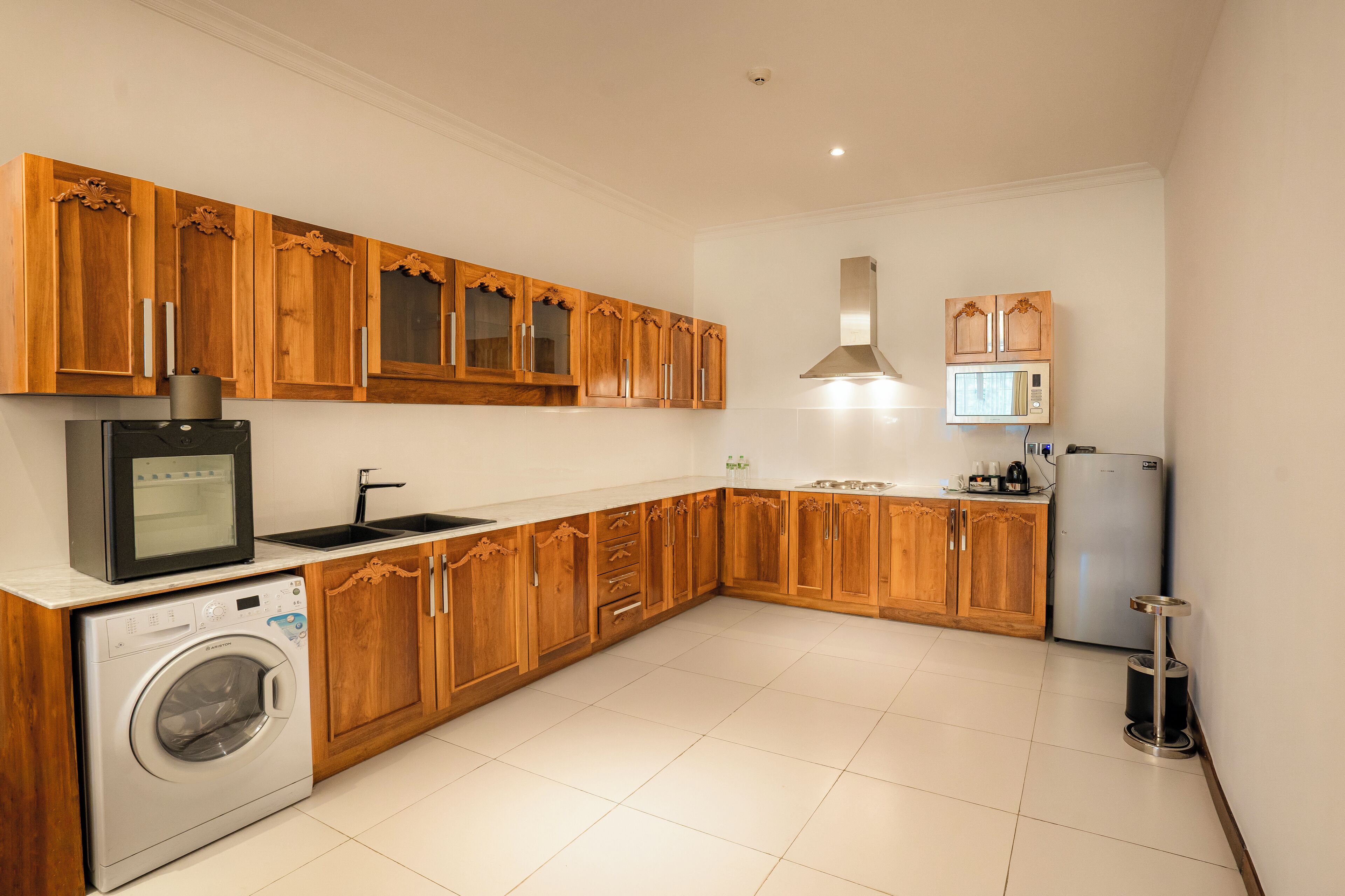 Una cocina con armarios de madera, lavadora, microondas y refrigerador.