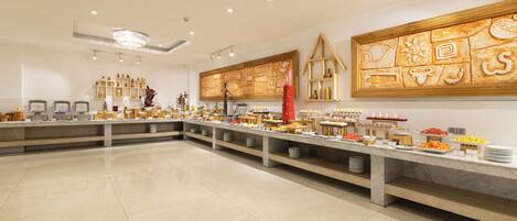 A buffet area with a marble countertop, various food items, and a decorative wall with cultural motifs.