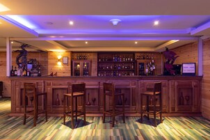 A bar area with wooden paneling, multiple liquor bottles, and bar stools.
