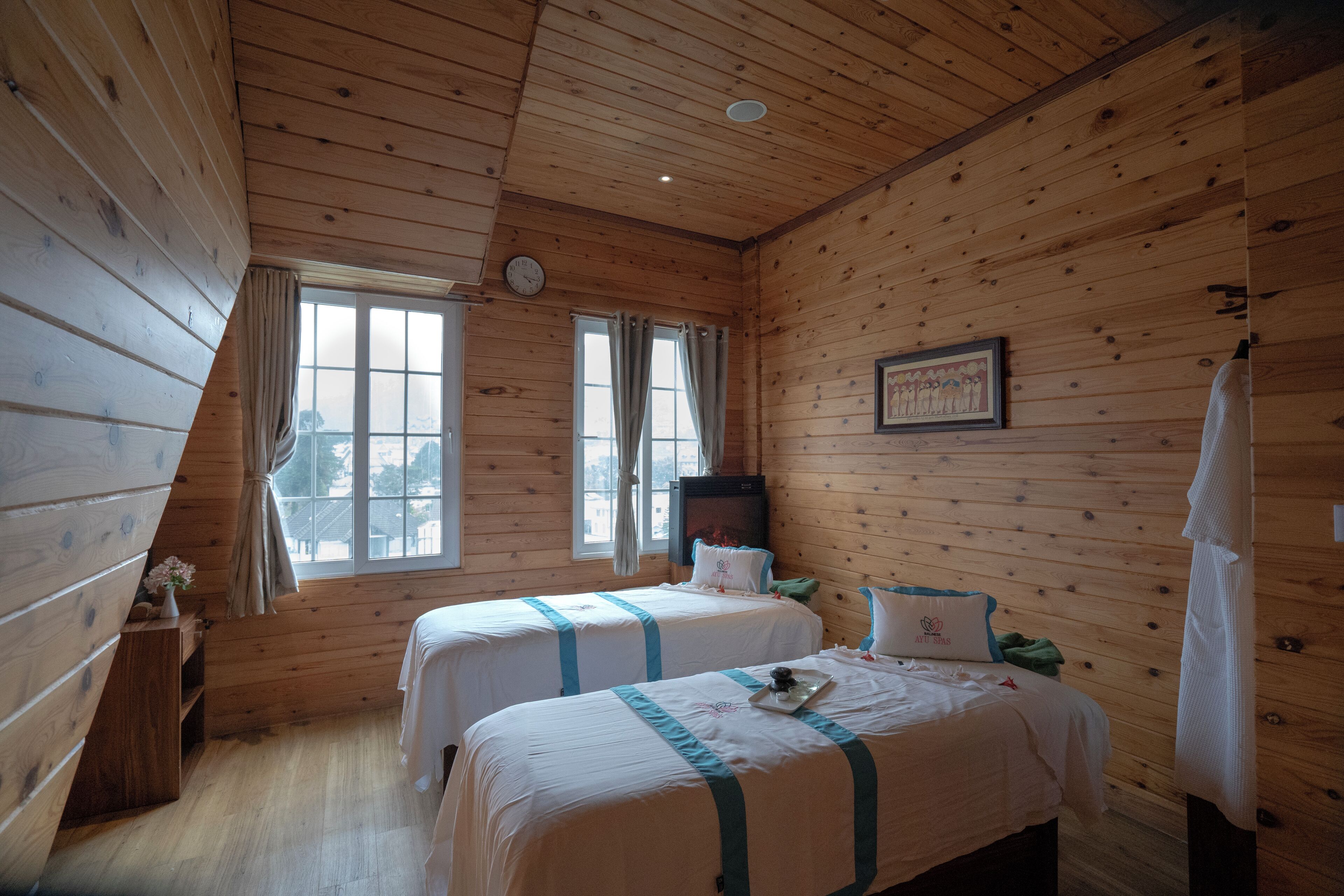 Una habitación tipo cabaña de madera con dos camas, una chimenea y una ventana con cortinas.