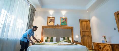 A hotel room with a large bed, wooden headboard, two framed horse paintings, a wooden wardrobe, and a green carpet.