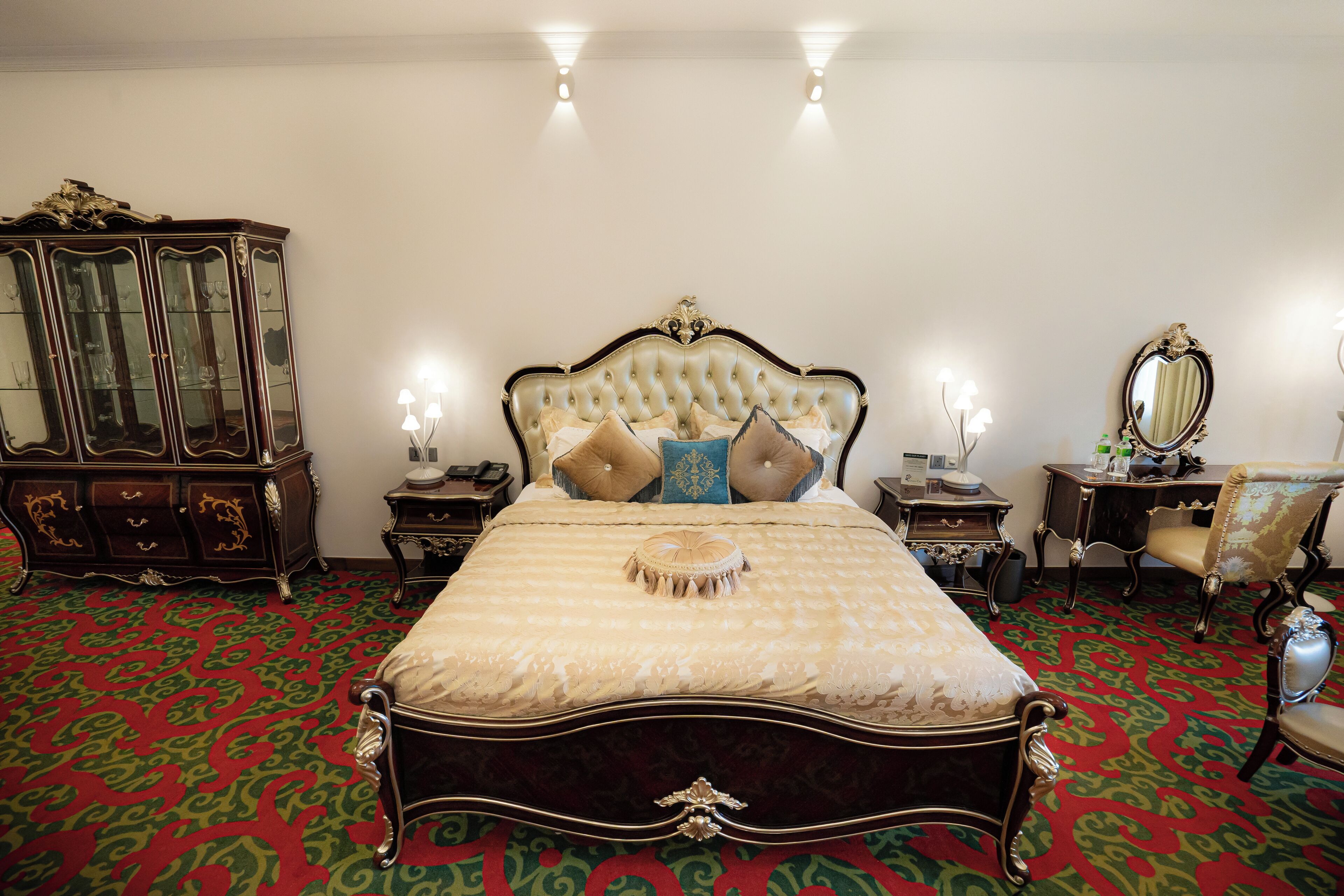 A bedroom with a large bed, a wooden dresser, a mirror, and a chair.