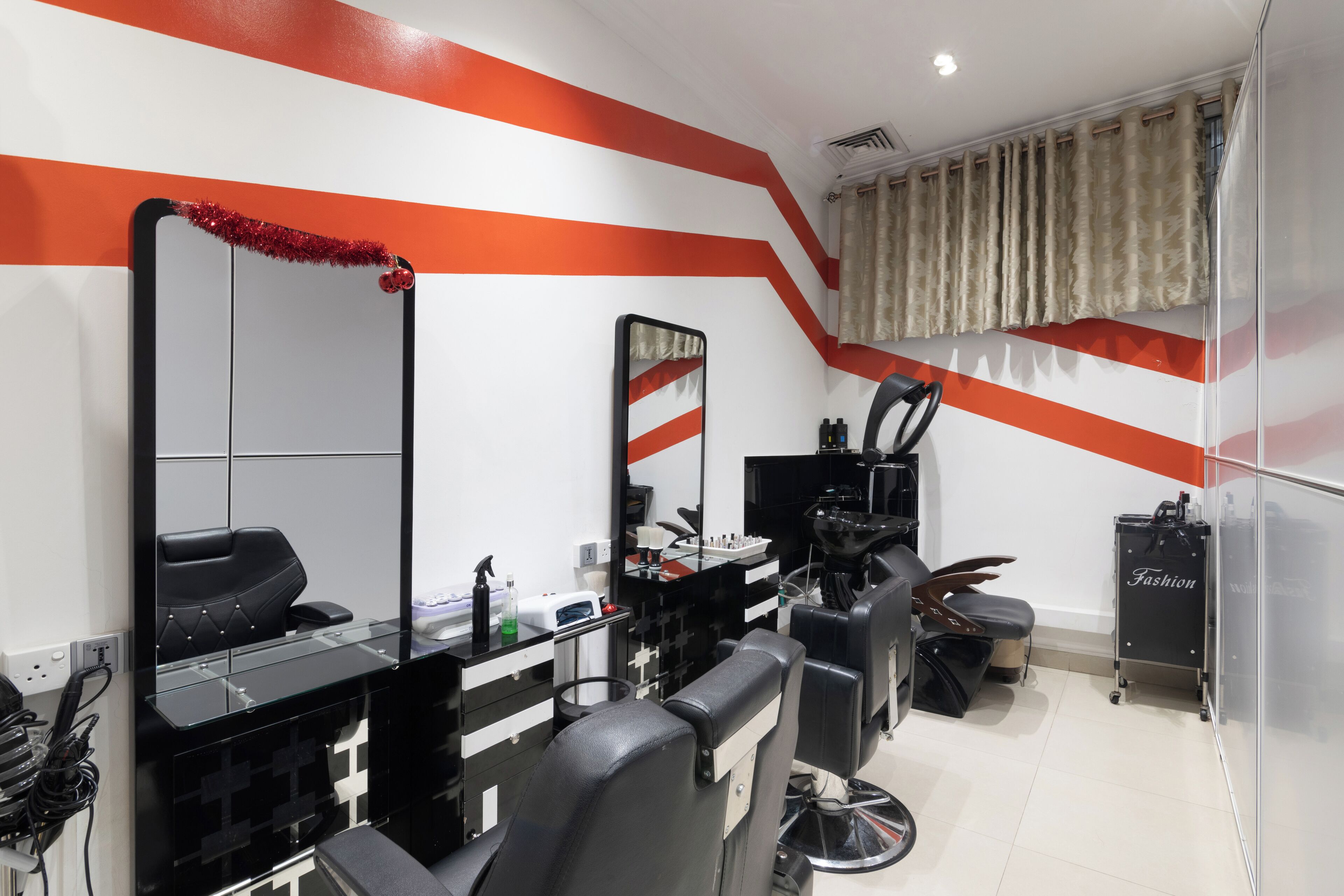 Un salon de coiffure moderne, avec une décoration en noir et blanc, un grand miroir et un rideau en fourrure.