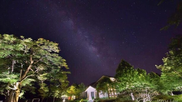 Una casa con un porche delantero y un cielo nocturno estrellado.