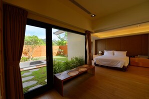 A modern bedroom with a large bed, a wooden bench, and a view of a garden through a sliding door. - Bear Forest Villa (Shoufeng)