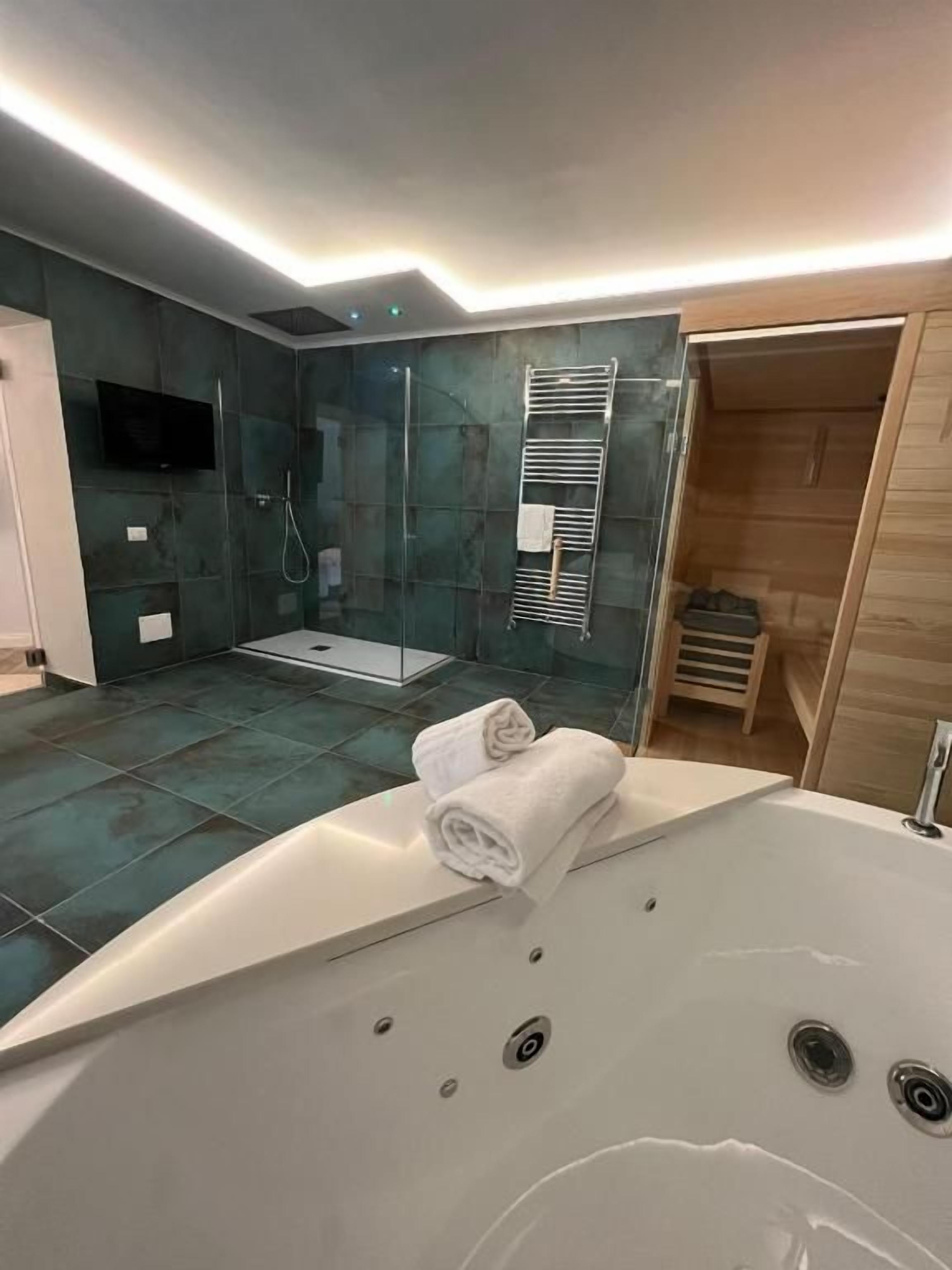 A modern bathroom with a large bathtub, a shower area, and a wooden vanity.