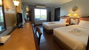 A hotel room with two beds, a desk with a computer, a chair, and a window with a view of the outdoors.