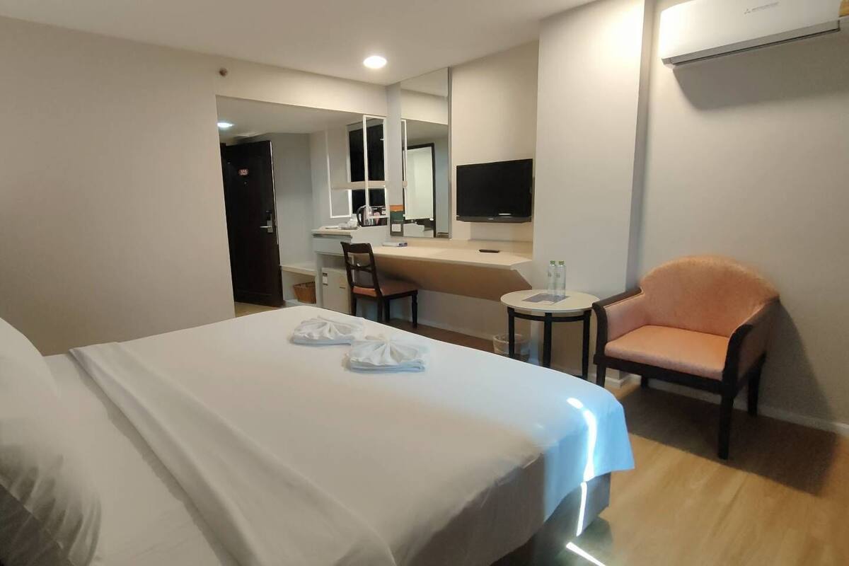 Una habitación de hotel con una cama, un escritorio, una silla y un televisor.
