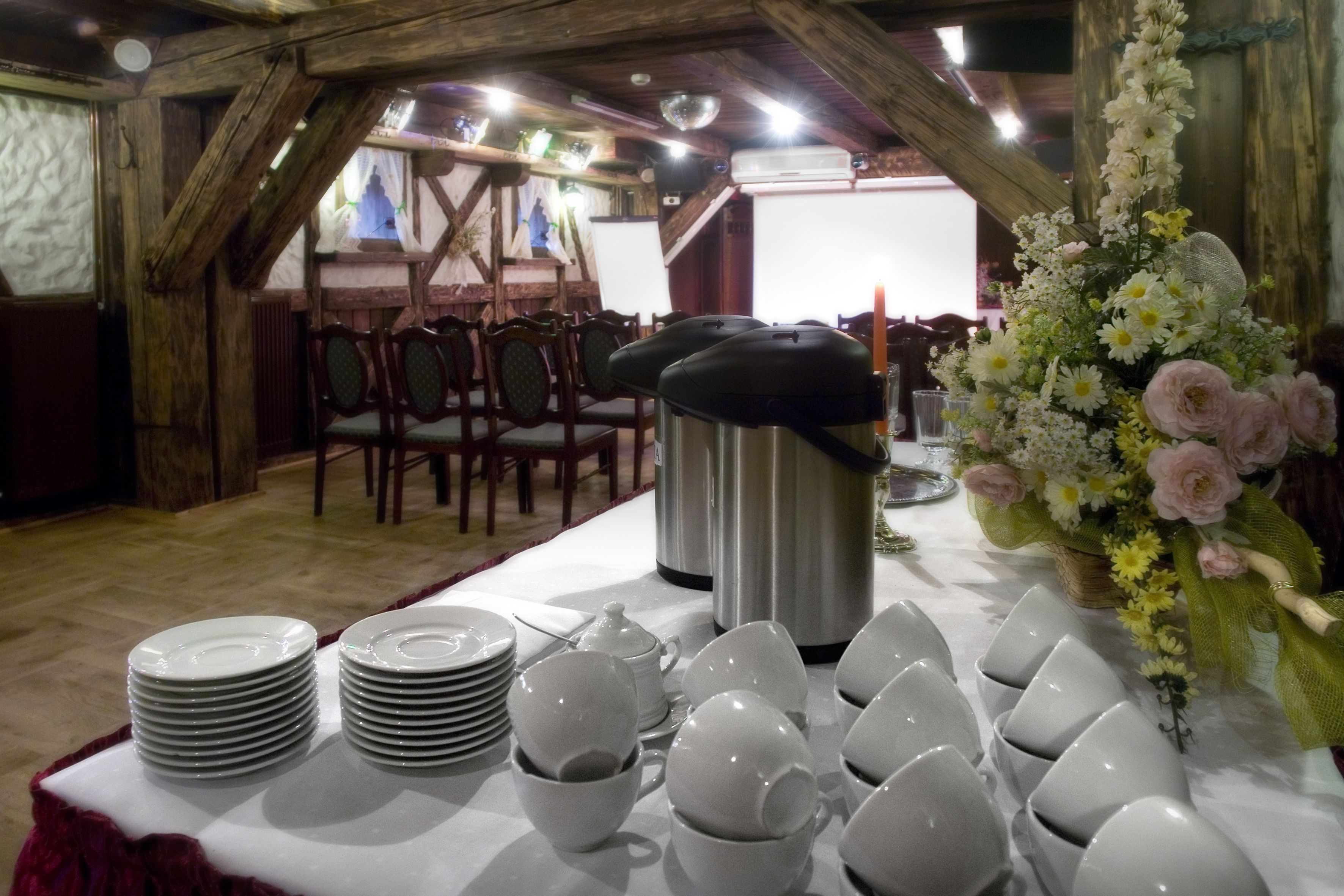 Un comedor con una mesa larga dispuesta para una comida, con platos, cuencos y tazas apilados.