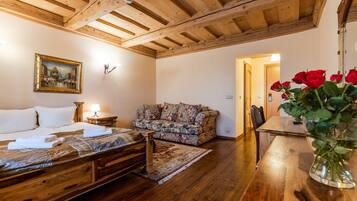 Una habitación acogedora con una cama de madera, un sofá floral, una mesa de madera y un jarrón con rosas rojas.