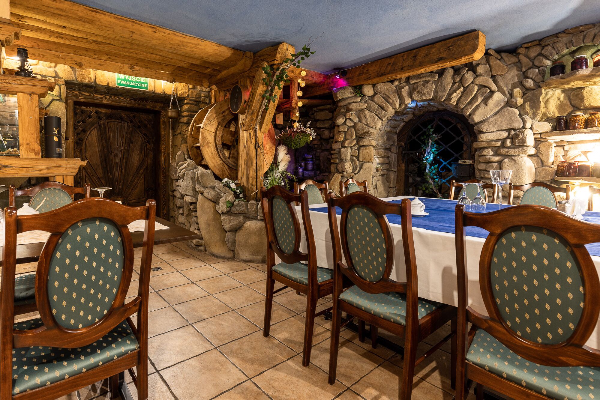 A dining area with stone walls, wooden furniture, and a stone fireplace.