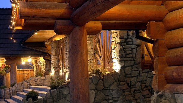 A log cabin with stone walls, wooden beams, and a stone staircase leading to the entrance. - Hotel Marysin Dwór (Katowice)