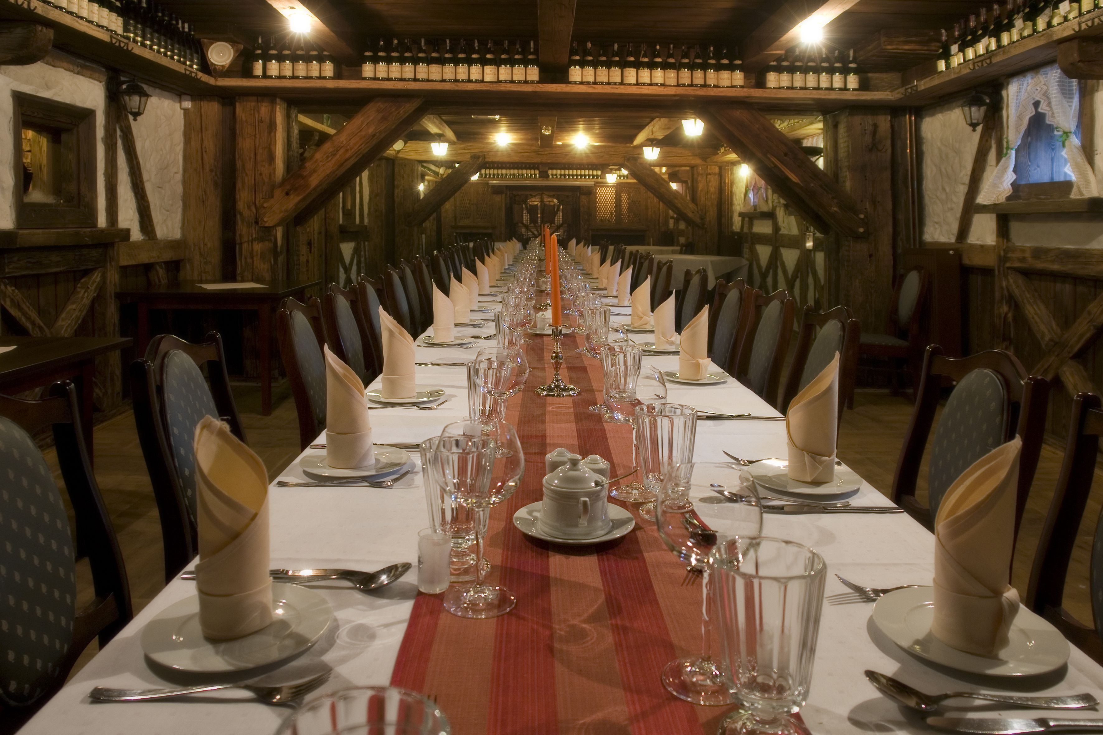 A long dining table set with white tablecloths, glassware, and folded napkins.