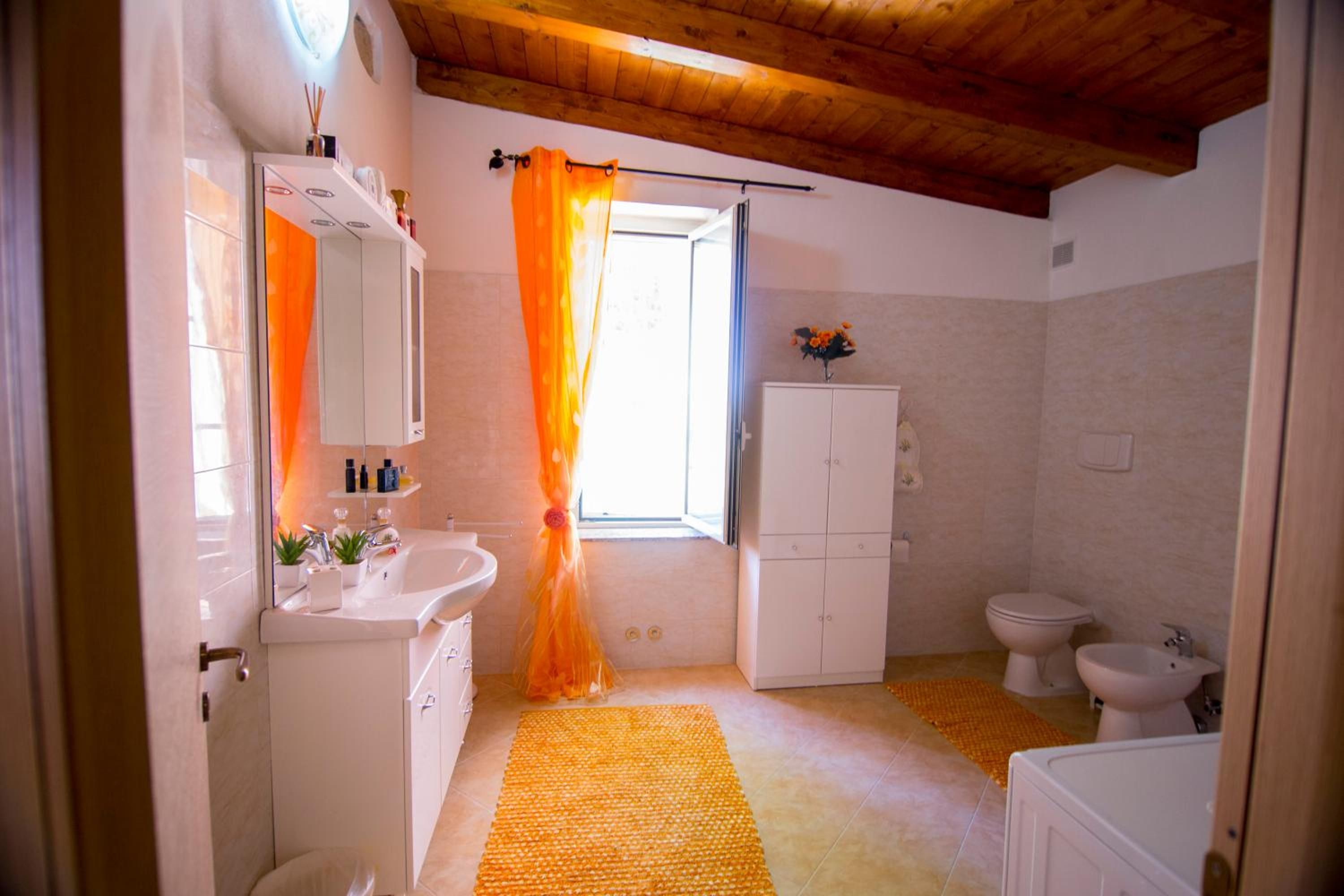 Un baño con lavamanos, espejo, armarios y un inodoro.
