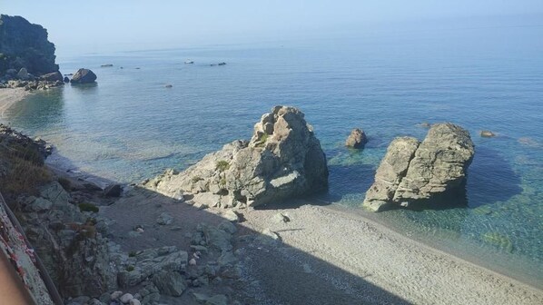 Un paisaje costero con aguas cristalinas, formaciones rocosas y una playa de arena.