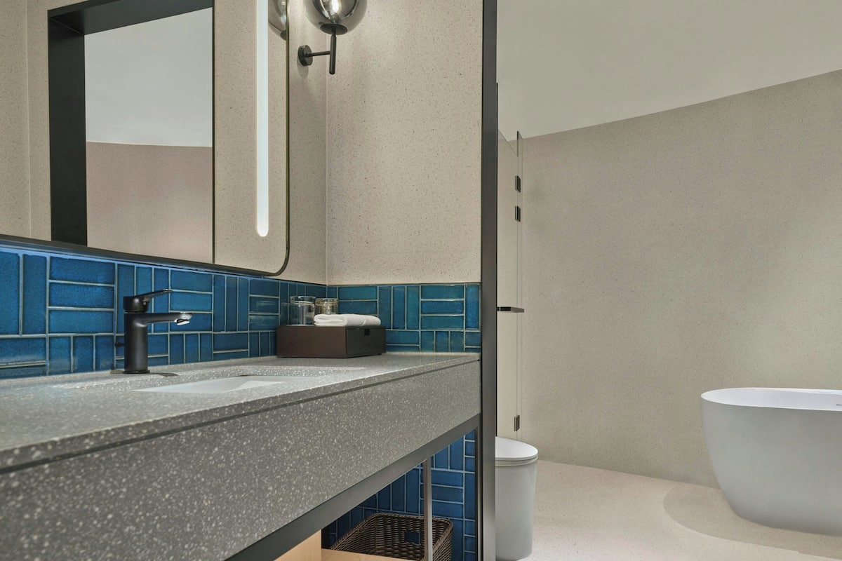 Ein Badezimmer mit einem grau gesprenkelten Waschtisch, einer schwarzen Armatur, einem weißen Waschbecken, einer weißen Toilette und blauen Fliesenwänden.