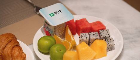 A plate with a croissant, watermelon, dragon fruit, and cheese on a table.