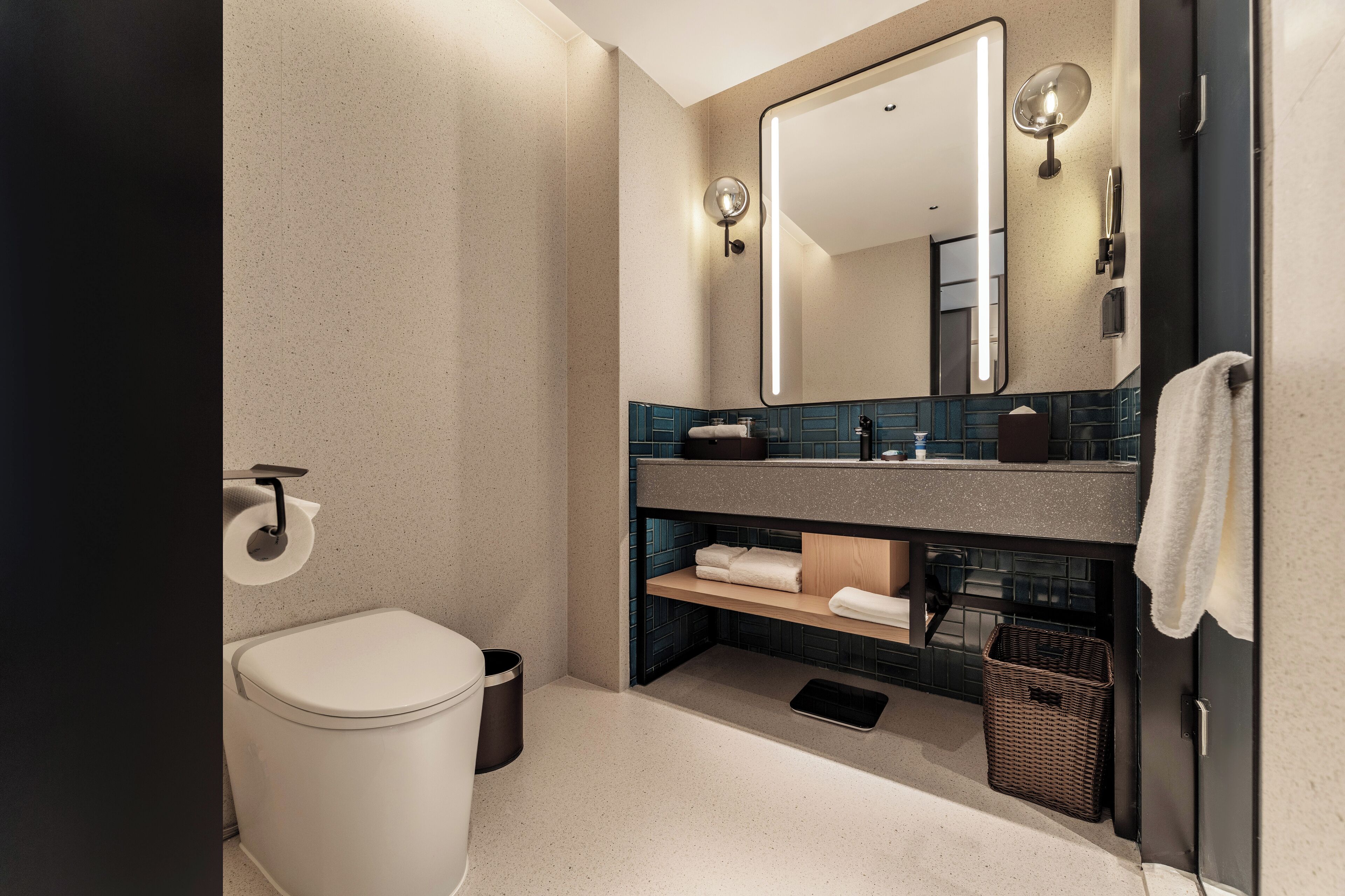 A modern bathroom with a toilet, sink, mirror, and towel rack.