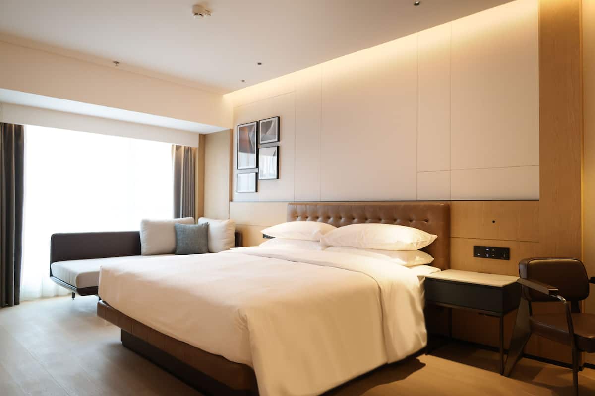 Ein modernes Hotelzimmer mit einem großen Bett, einem Schreibtisch und einem Stuhl.