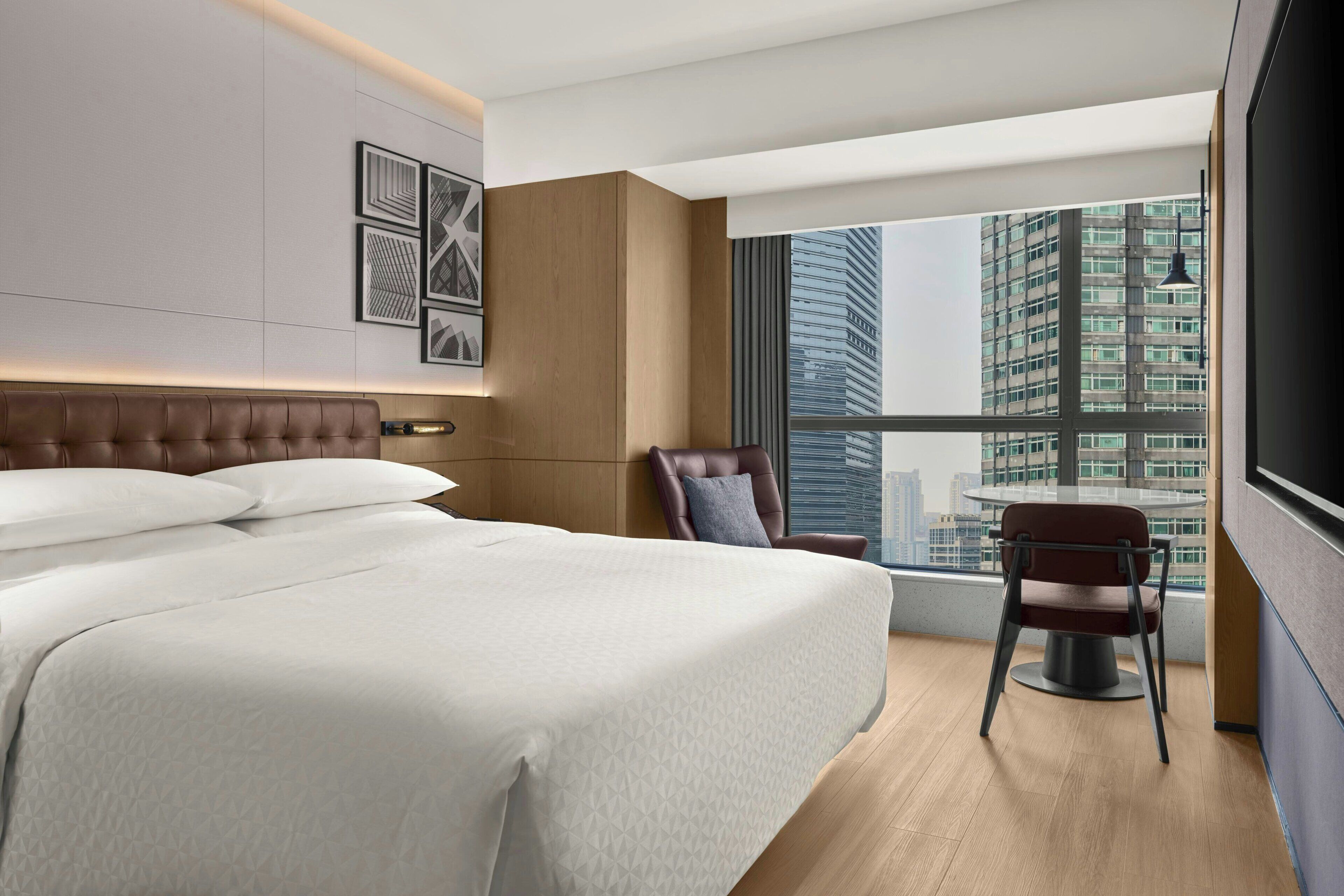 Una camera d'albergo moderna con un letto grande, un'area salotto e vista sulla città.
