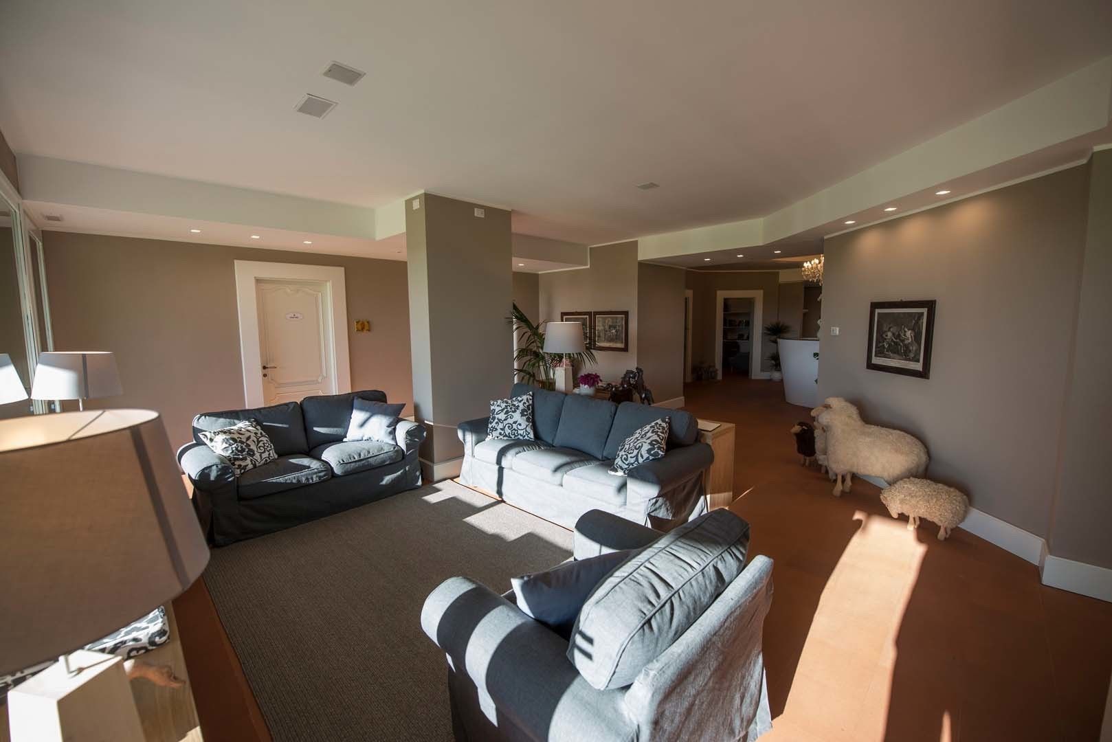 Ein geräumiges Wohnzimmer mit zwei Sofas, einem Couchtisch und einer Lampe. Dekorative Kissen und ein kleiner Tisch mit einer Lampe sind ebenfalls vorhanden. Eine Tür führt in einen anderen Raum.