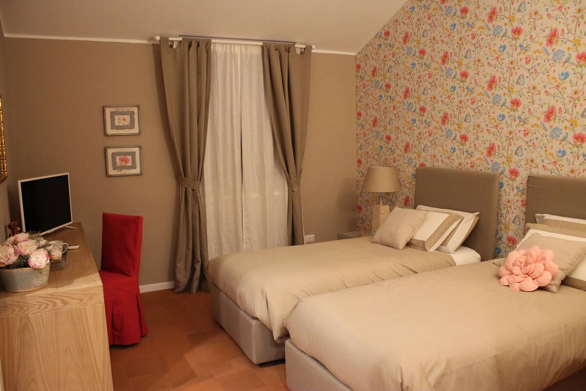 Een slaapkamer met twee bedden, een bureau, een stoel en een televisie.