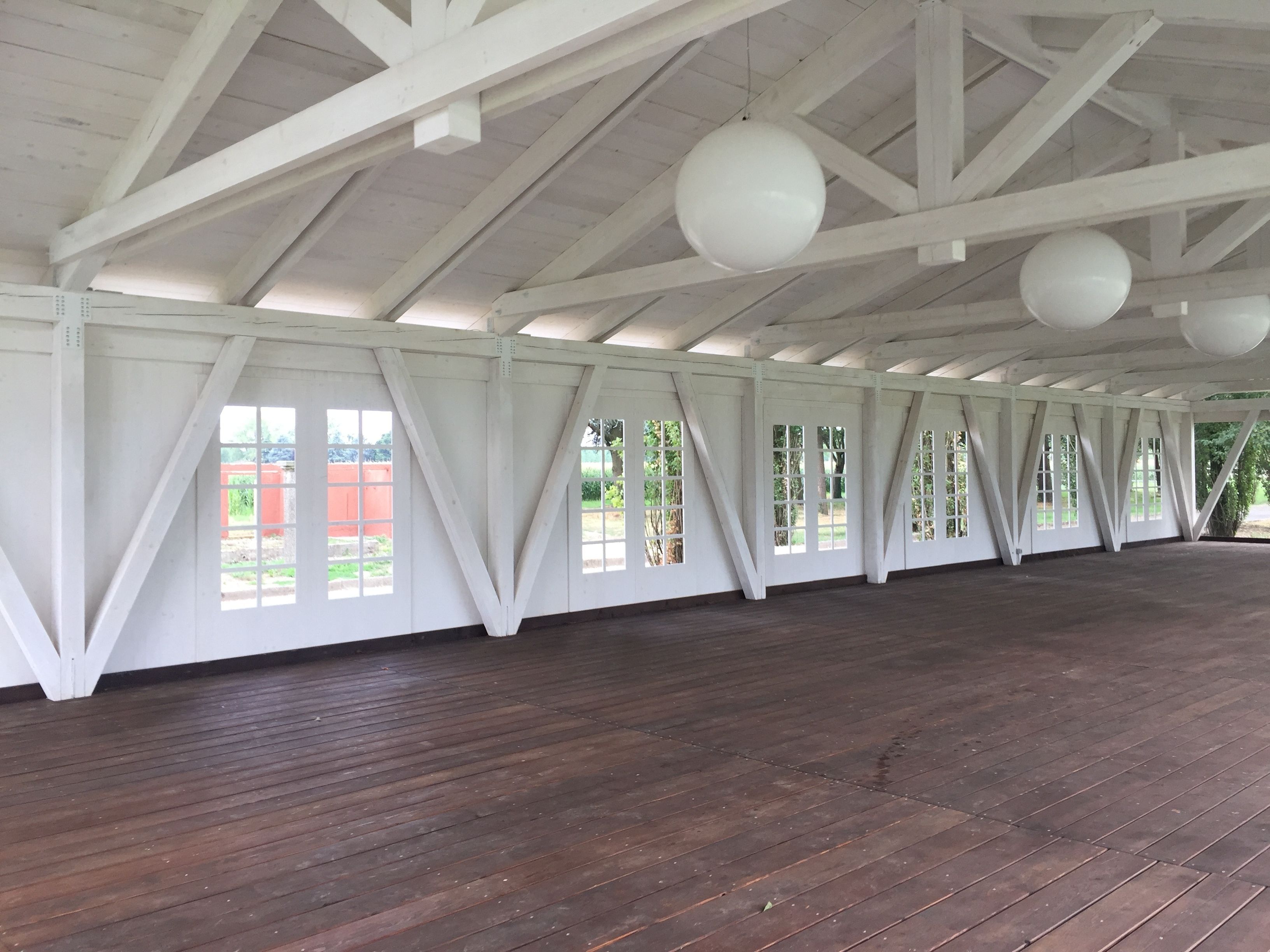 Un amplio espacio interior con techos altos y vigas de madera blanca.
