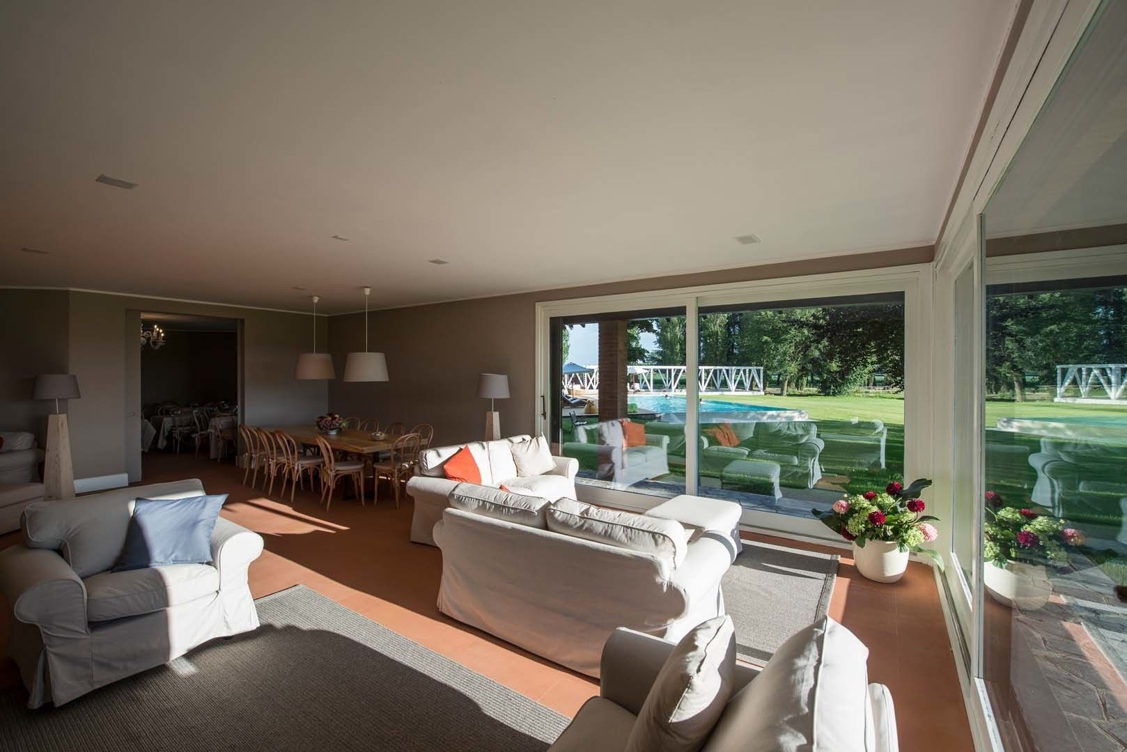 Un salon spacieux doté d’une grande fenêtre, d’un coin repas et offrant une vue sur une piscine.
