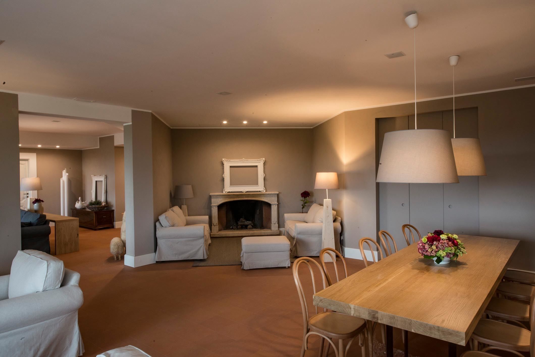 Uma sala de estar ampla com lareira, uma área de jantar com mesa de madeira e um canto de estar aconchegante.