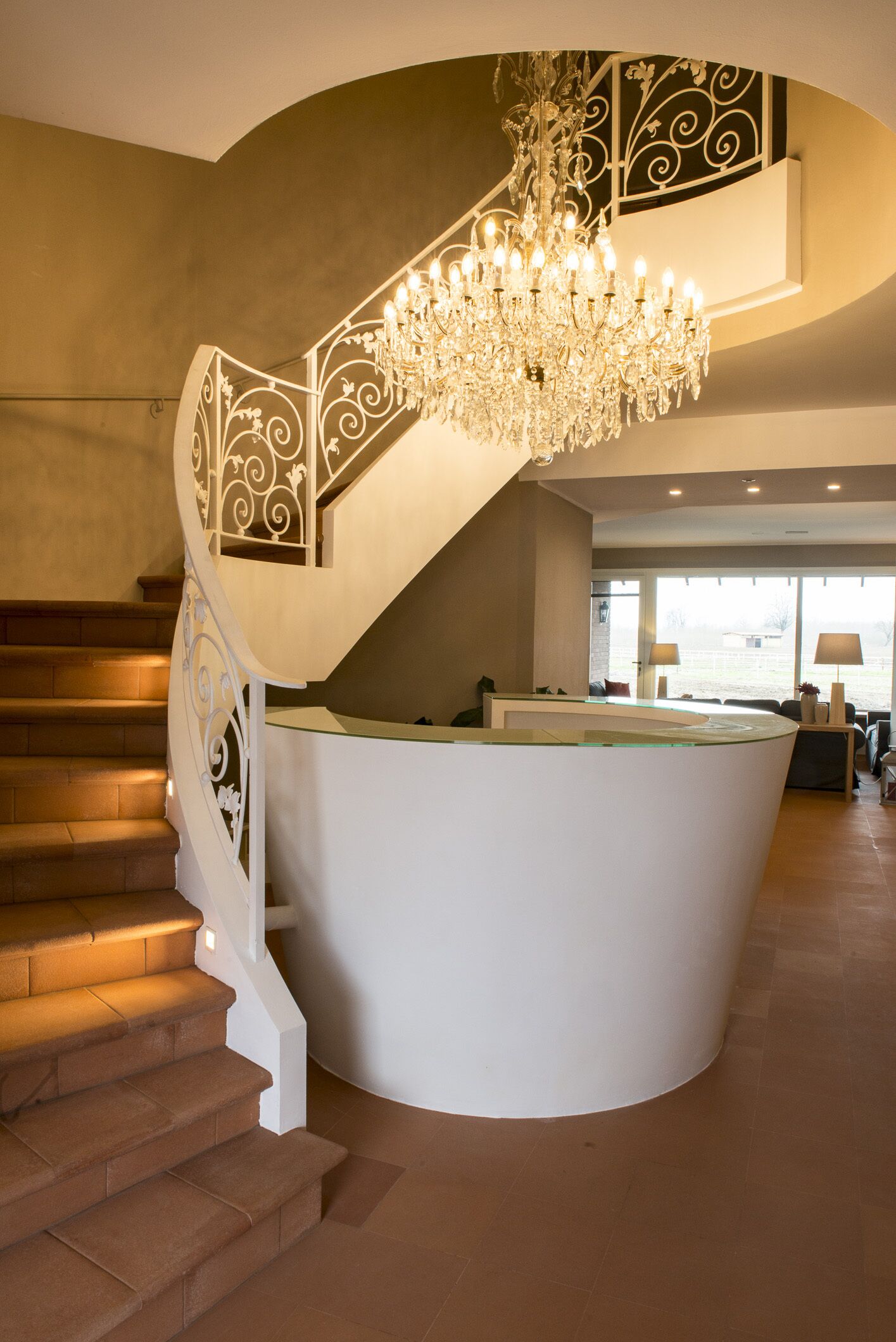 Una imponente escalera con barandilla blanca y un gran candelabro.