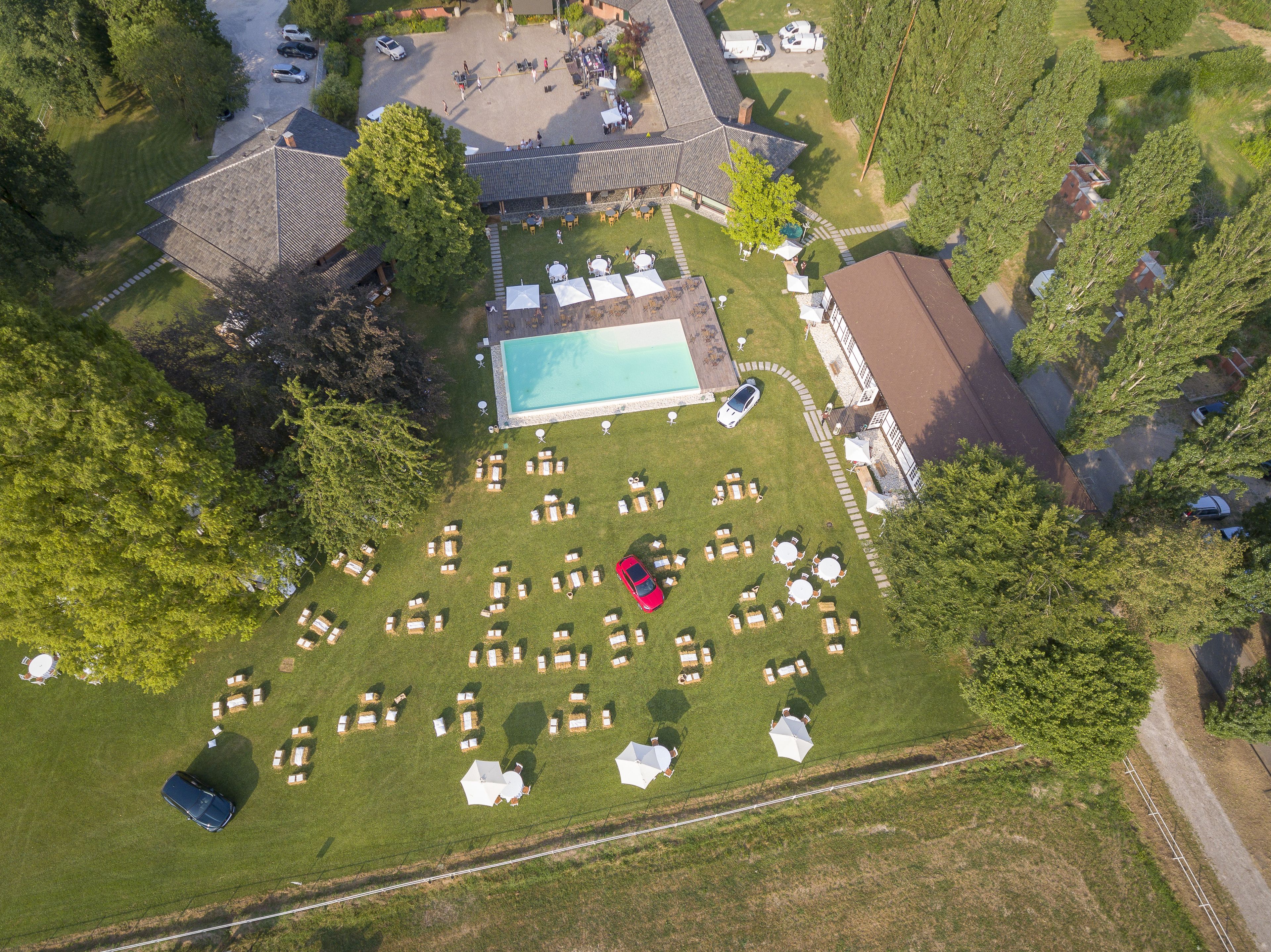 An aerial view of a property with a swimming pool, sun loungers, and a parking area.