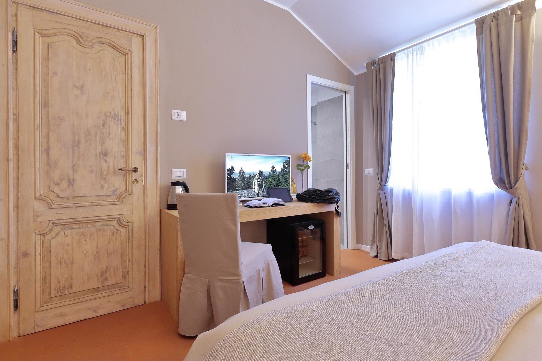 Une chambre d’hôtel comprenant un lit, un bureau avec un ordinateur, une chaise et une armoire.