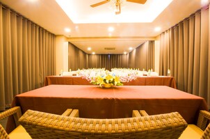 Un salón de conferencias con una larga mesa, sillas de mimbre y un ventilador de techo.
